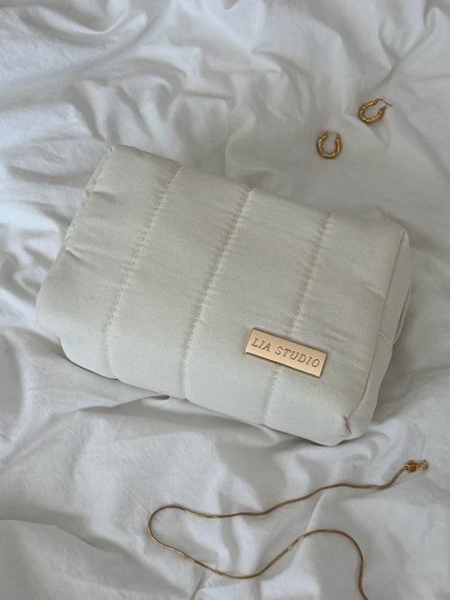 White makeup bag with 'LIA STUDIO' label on a white textured surface.