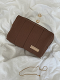 Brown makeup bag with a visible brand logo on a white textured surface