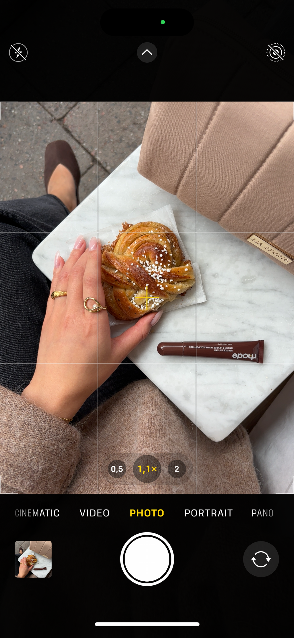 Hand holing pastry close to makeup bag Chai on marble table